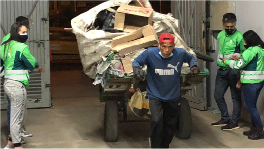 En la imagen: Un reciclador lleva su carreta con una carga de gran dimensión compuesta por cajas de cartón y material reciclable. Esta imagen es en un Centro Transitorio de Cuidado al Carretero. 