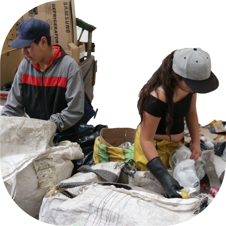 Imagen de fondo, Dos personas al interior de una bodega hacen reciclaje de materiales.