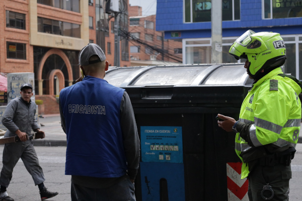 Un policía interpone una multa a un ciudadano por dejar residuos en un contenedor fuera del horario establecido para este fin.