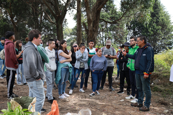 Contratista de la UAESP explica a los estudiantes cómo plantar los árboles en el punto crítico recuperado por la entidad.