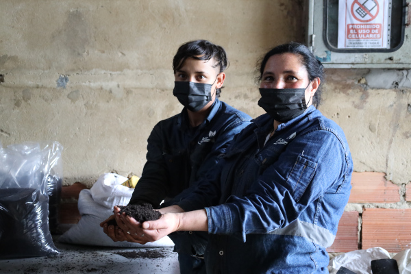 Dos recicladores exhibiendo en sus manos el abono orgánico que ha producido la planta MyM Universal.