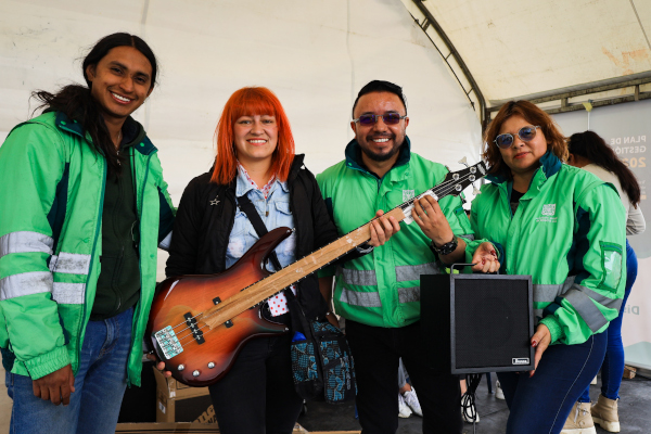 Funcionarios de la UAESP le entregan una guitarra eléctrica a una persona de la comunidad de Los Mochuelos.