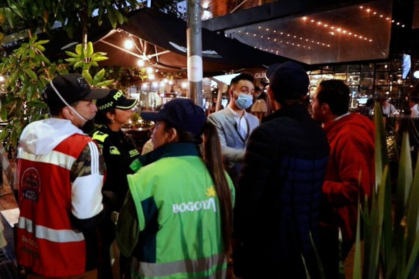 Foto de noche. Exteriores. En el fondo se ven funcionarios de la UAESP sensibilizando a comerciantes de la Zona T, sobre el adecuado manejo de residuos.