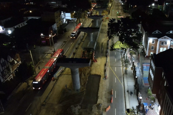 Vista aérea nocturna del corredor de la avenida Caracas, donde se observan las obras del tramo 5 de la Línea 1 del Metro de Bogotá y la operación de TransMilenio.