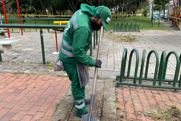 Operario de aseo interviene el césped de un parque.