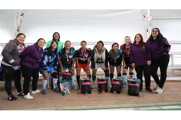 Las mujeres que jugaron el torneo de microfútbol lucen sus medallas, cactus, libros y anchetas.