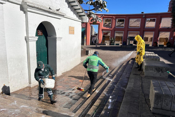 Dos operarios de aseo y un funcionario de la UAESP participando en la jornada de limpieza en el Chorro de Quevedo, en La Candelaria, en el centro de Bogotá.