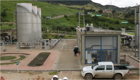 En la imagen: Imagen de la Planta Biogás Colombia, a la derecha tres chimeneas cilíndricas en concreto de gran altura, a la izquierda el cuarto de máquinas, de fondo un paisaje verde.