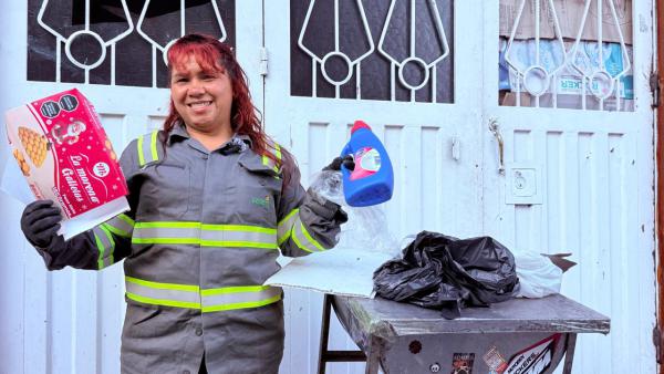 Mujer con uniforme de reciclador con botella plastica en la mano