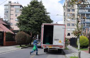 El camión de la ruta de residuos orgánicos recogiendo material en unidades residenciales (recicladores con uniforme, recogiendo el material)