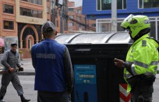 Un policía interpone una multa a un ciudadano por dejar residuos en un contenedor fuera del horario establecido para este fin.