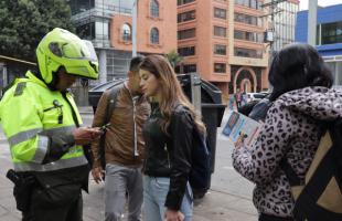 Un policía junto a gestores de la UAESP realiza una jornada de comparendos en la localidad de Chapinero.