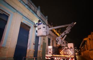 Un técnico de Enel Colombia interviene y repara una de las luminarias de alumbrado público que está ubicada en una de las fachadas de las viviendas del Centro Histórico de Bogotá. 