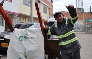  Foto en el interior de una bodega. En ella se ve a un reciclador con el dedo arriba, en actitud positiva. El reciclador porta el uniforme