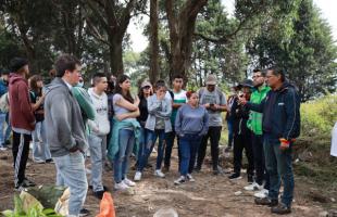 Contratista de la UAESP explica a los estudiantes cómo plantar los árboles en el punto crítico recuperado por la entidad.