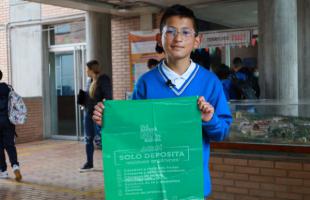 Estudiante del colegio José Celestino Mutis posa con una bolsa verde en donde se depositan los residuos orgánicos.
