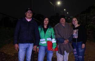 Imagen de la gestora social de alumbrado público, Stefany Tarazona, junto a residentes e integrantes de la comunidad del barrio Fiscala Alta de Usme, tras el proceso de ampliación del servicio de alumbrado con nuevos 20 postes y luminarias.