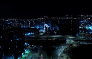 Foto panorámica de la Avenida Ciudad de Cali, a la altura de la Autopista Sur, en la noche, se ve la glorieta de esta intersección con mucho movimiento de vehículos y el cambio de iluminación a luz led.