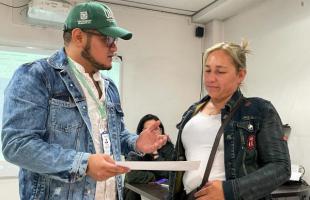 Profesional de la Entidad, entrega diploma a mujer carretera de oficio.