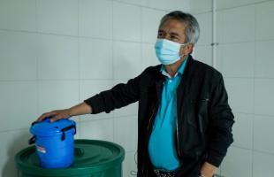 Habitante del Conjunto residencial en el cuarto de shut, haciendo disposición de residuos con un valde pequeño azul en sus manos.