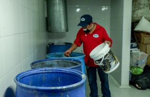 Conserje del conjunto haciendo limpieza de las canecas de recolección de residuos.