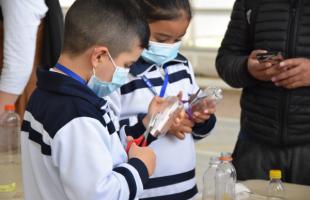 Niños aprenden a hacer artesanías con plástico reciclado.