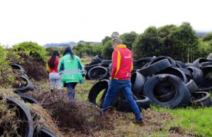 Se observa un grupo de funcionarios del Distrito caminando entre varias llantas que están tiradas a su alrededor.