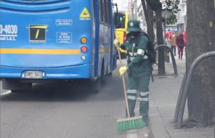 Operaria de aseo realiza barrido en vía pública. 