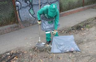 Operaria de aseo vestida de verde recoge residuos en el piso