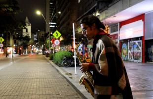 Imagen de un joven tocando saxofón en la Carrera Séptima con Calle 12 y de fondo luminarias en tecnología led.