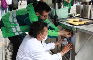 Contratista de la UAESP pega, junto a comerciante del centro de la ciudad, afiche de No Sea Mugre con Bogotá.