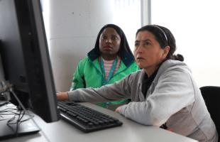 Mujer recibe asesoramiento en temas de cómputo por parte de una funcionaria de la UAESP.