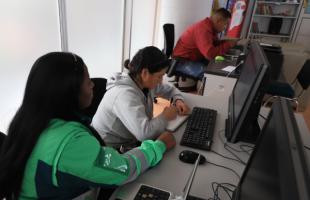 Mujer escrbie en su cuaderno los apuntes de su clase de sistemas. 