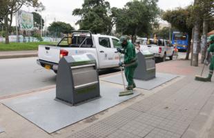 Operario de aseo limpia uno de los contenedores soterrados.