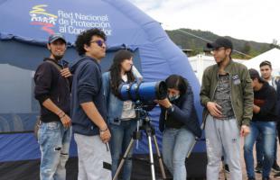 Asistentes a la Feria de Servicios observan a través de unos telescopios.