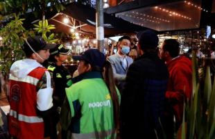 Foto de noche. Exteriores. En el fondo se ven funcionarios de la UAESP sensibilizando a comerciantes de la Zona T, sobre el adecuado manejo de residuos.