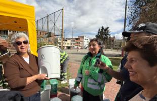 Comerciante recibiendo una caneca que entrega la UAESP