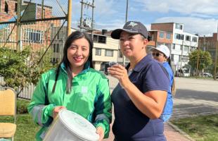 Subdirectora, Yira Bolaños, entrega una caneca blanca de reciclaje