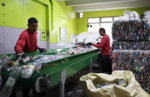 Dos recicladores están separando material plástico en una banda transportadora.