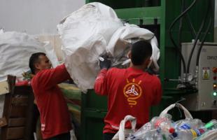Dos recicladores manipulan material plástico ponen en la máquina compactadora.