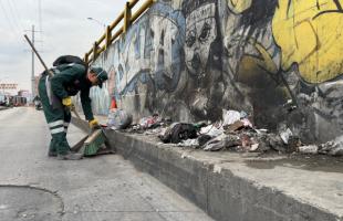Operario echando en bolsa negra resiudos no aprovechables que estaban tirados en la calle.