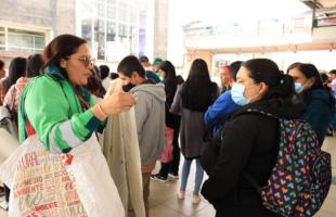 Gestora de la UAESP, con chaqueta institucional, explica a usuaria de TransMilenio sobre el uso de la bolsa blanca para residuos aprovechables, durante una jornada de sensibilización sobre adecuada separación y disposición de residuos.
