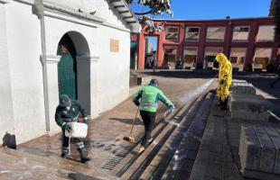 Dos operarios de aseo y un funcionario de la UAESP participando en la jornada de limpieza en el Chorro de Quevedo, en La Candelaria, en el centro de Bogotá.