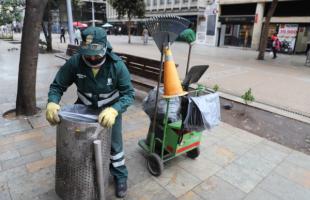 Operario de barrido habilitando una cesta pública. 
