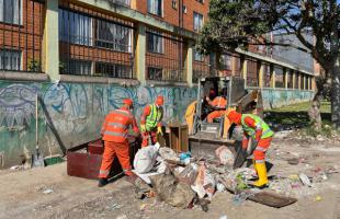 Operarios de Aguas de Bogotá recogiendo escombros y residuos voluminosos del espacio público.
