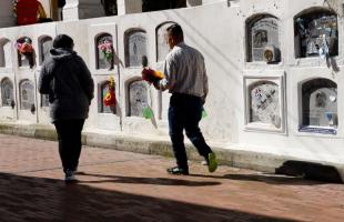 Dos usuarios visitan el Cementerio Distrital Central. Caminan hacia uno de los mausoleos.