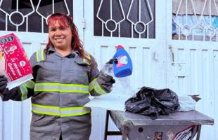 Mujer con uniforme de reciclador con botella plastica en la mano